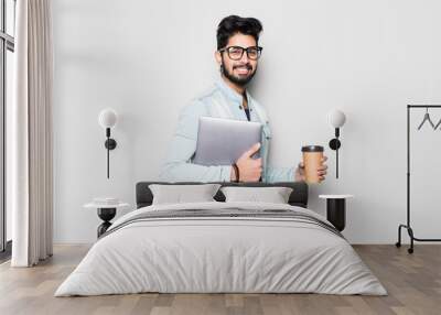 Young indian man holding laptop and take away coffee white standing on white background Wall mural